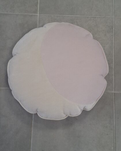 Okrągła poduszka w kształcie kwiatu w dwóch odcieniach pastelowego różu leżąca na szarej podłodze kafelkowej