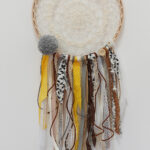 Ozdobny łapacz snów z koronkowej siatki i wstążek w różnych wzorach oraz kolorach żółtego, brązu i bieli