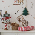 Świąteczna dekoracja na białej komodzie z tabliczkami, koszykiem i paskowanym podłużnym poduszka