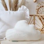 Biała poduszka w kształcie chmury i klasyczna poduszka na wiklinowym łóżku z ozdobami z trawy pampasowej