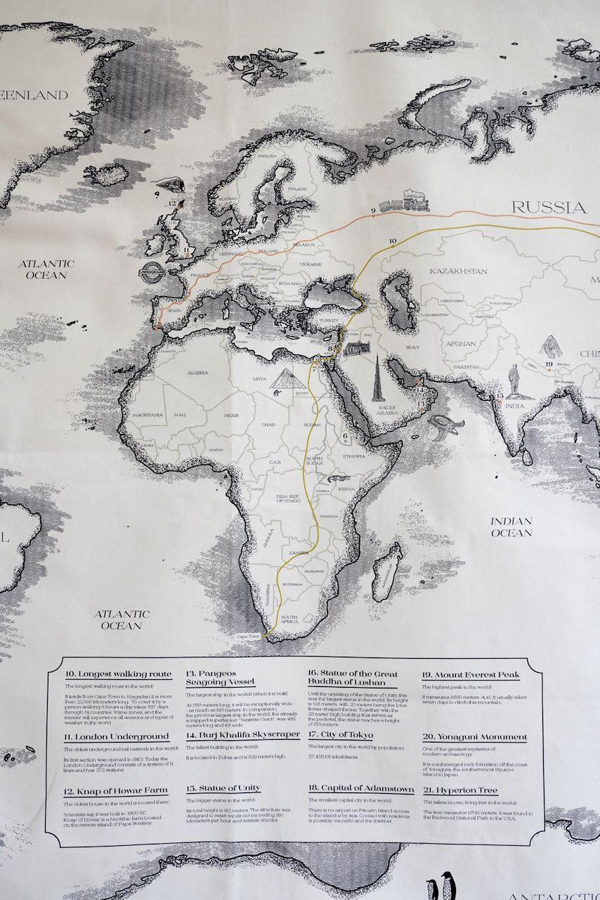 Mapa świata z zaznaczonymi trasami i najważniejszymi punktami oraz opisami na dole w czarno-białym stylu.