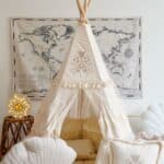 Dziecięcy biały namiot tipi z ozdobnymi poduszkami i lampką kwiatową na tle mapy świata.