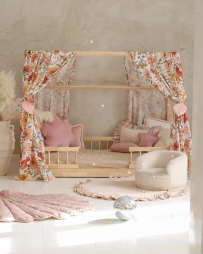 Przytulny pokój dziecięcy z łóżkiem baldachimowym udekorowanym kwiatowymi zasłonami i różowymi poduszkami