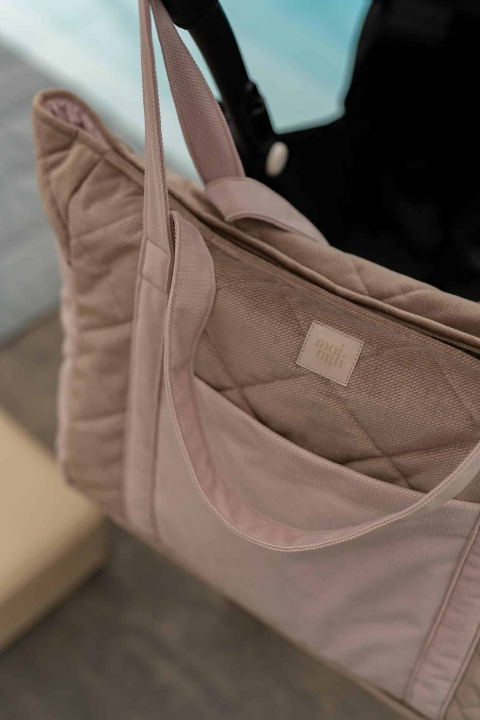 Beżowa torba tekstylna z długimi paskami zawieszona na uchwycie w jasnym wnętrzu