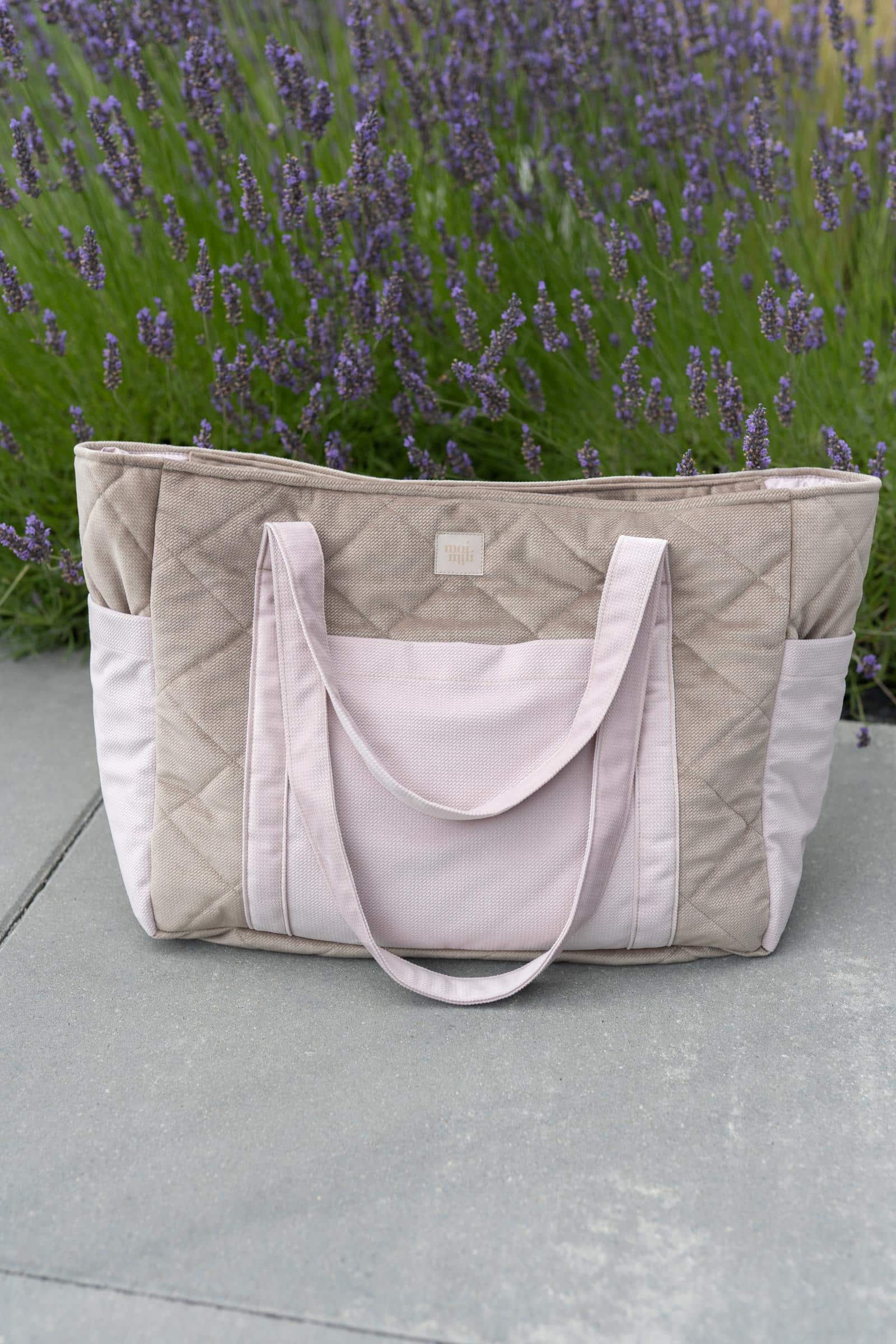Beżowo-różowa pikowana torba z długimi uchwytami na tle fioletowych kwiatów lawendy