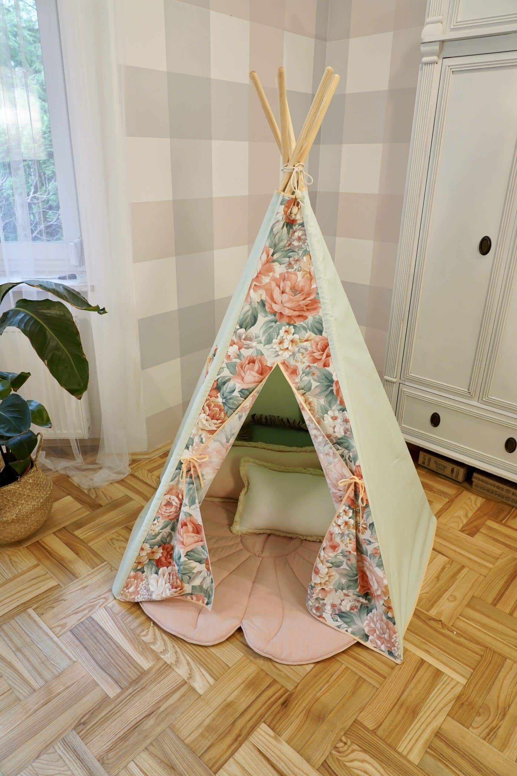 Dziecięcy namiot tipi z kwiatowym wzorem i poduszką na drewnianej podłodze w pokoju z rośliną przy oknie