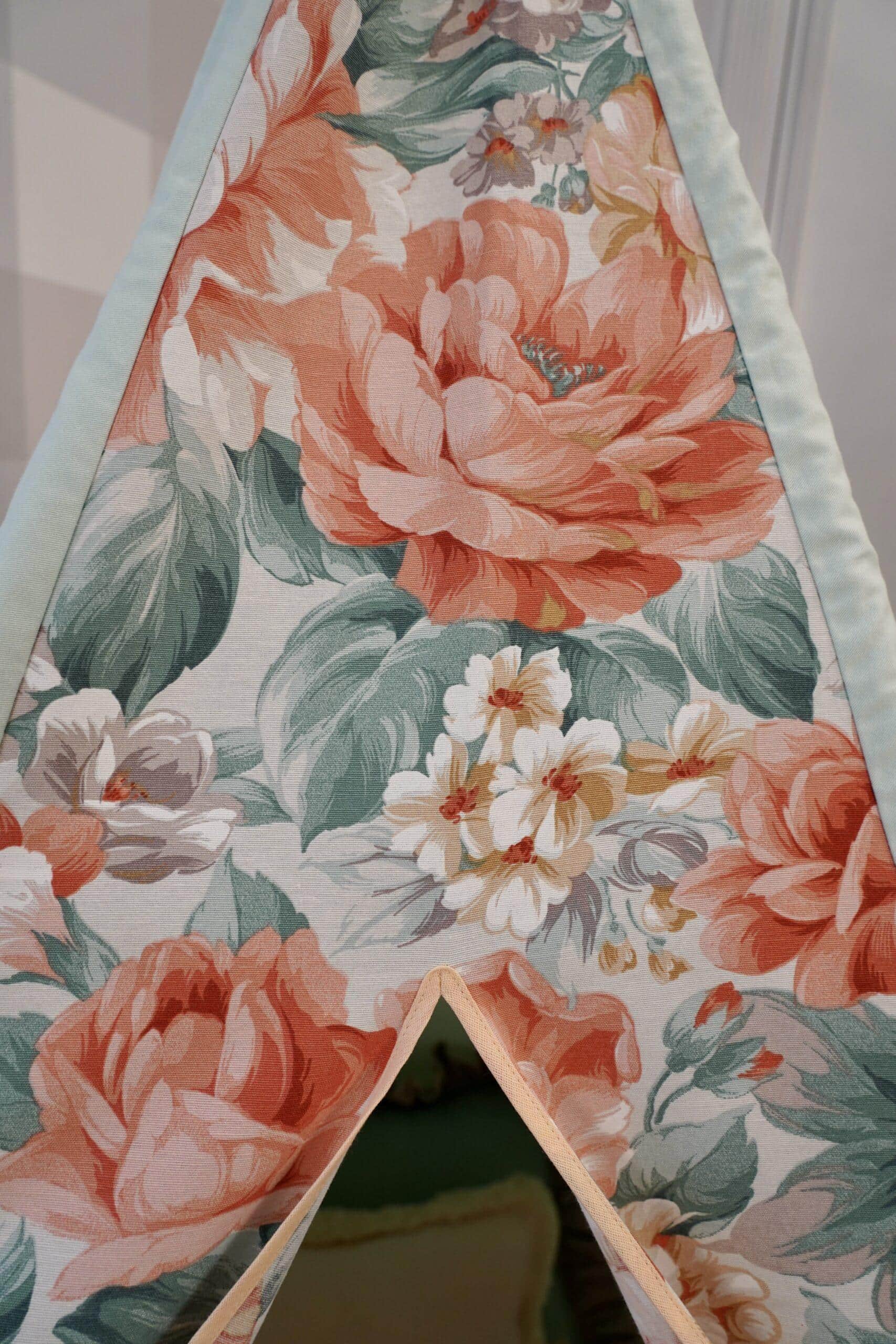 Tkanina z wzorem dużych różowych i białych kwiatów z zielonymi liśćmi obramowana jasnoniebieską lamówką