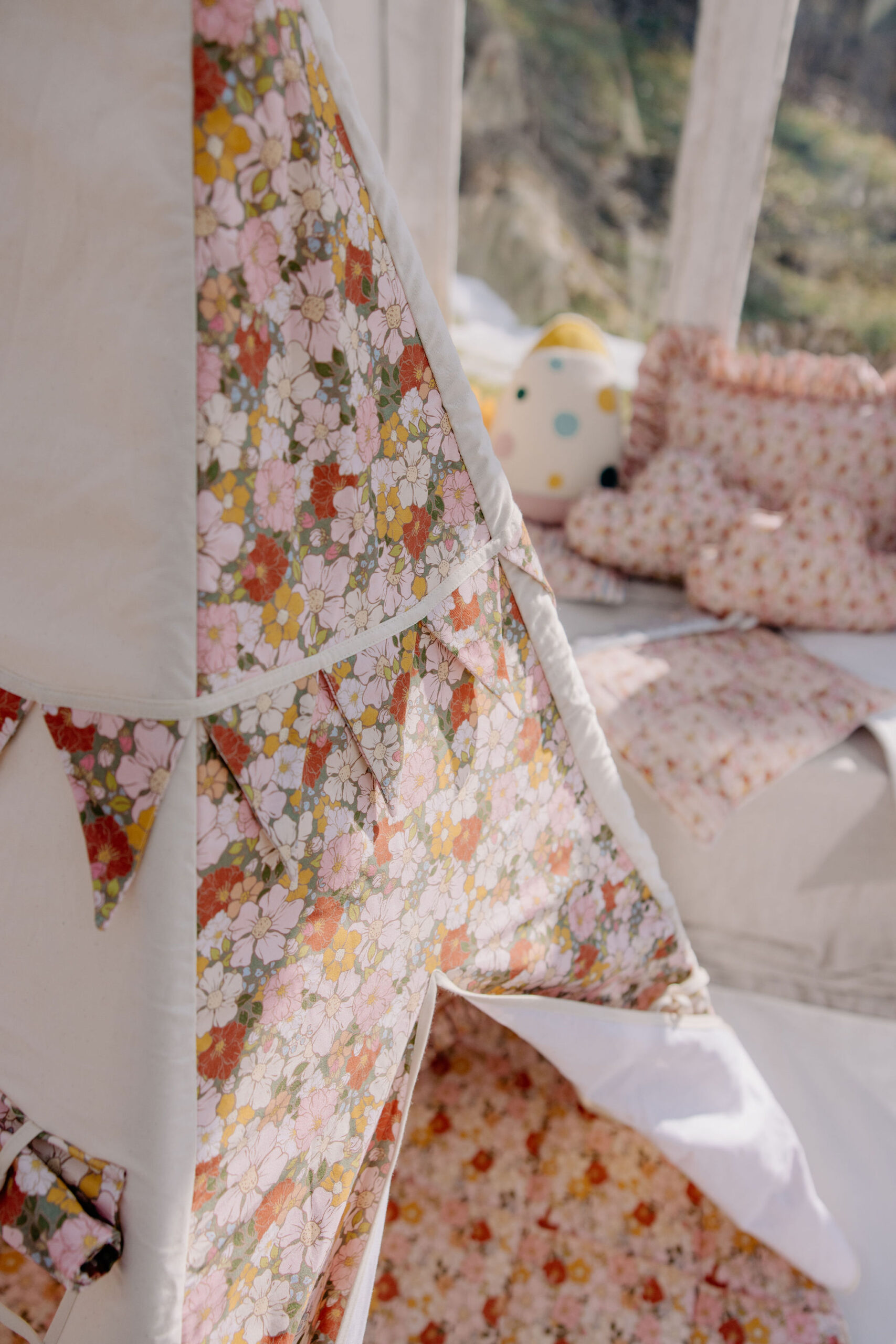 Kolorowy dziecięcy namiot tipi z kwiatowym wzorem, z miękkimi poduszkami w tle na tarasie