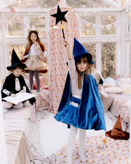 Dzieci przebrane za czarodziei i księżniczki bawiące się w jasnym, dekorowanym pomieszczeniu sypialnym