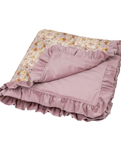 Złożony koc w odcieniach różu z falbankami i wzorem kwiatowym na jasnym tle