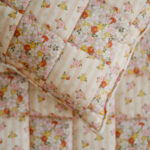 Koc i poduszka z pikowanym kwadratowym wzorem w kwiaty i paski w pastelowych kolorach