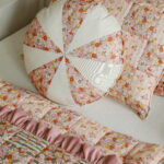 Okrągła poduszka i kwadratowa poduszka w pastelowe kwiatowe wzory na jasnym tle łóżka z pikowanym narzutą