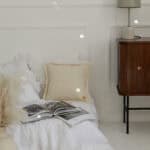 Przytulne łóżko z białą pościelą, kremową poduszką i otwartą książką w jasnym, minimalistycznym wnętrzu