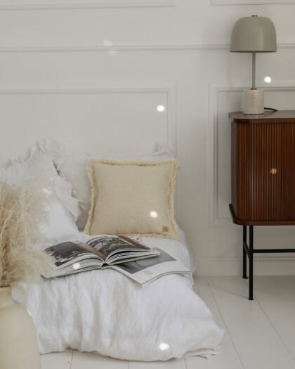 Przytulne łóżko z białą pościelą, kremową poduszką i otwartą książką w jasnym, minimalistycznym wnętrzu