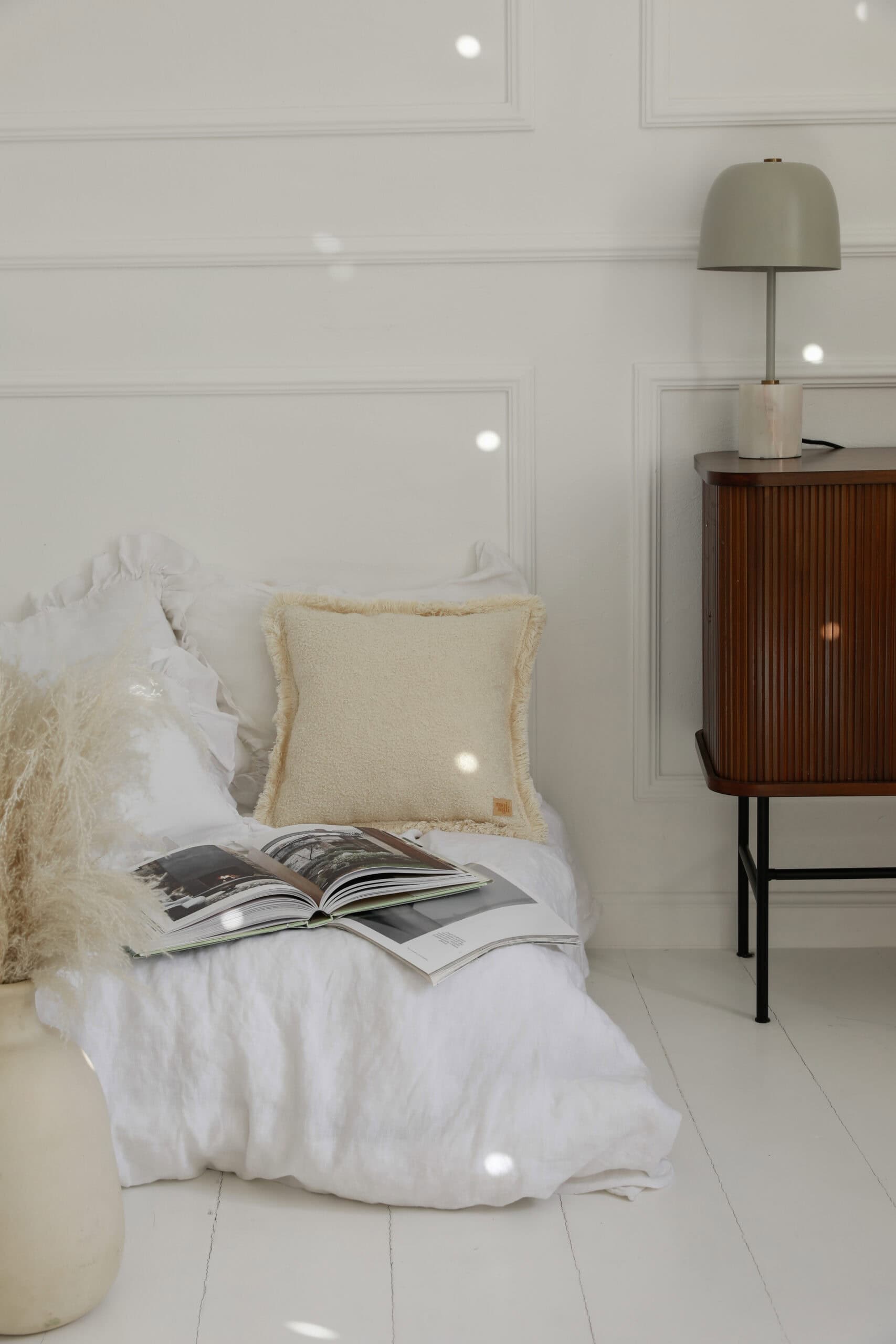 Przytulne łóżko z białą pościelą, kremową poduszką i otwartą książką w jasnym, minimalistycznym wnętrzu