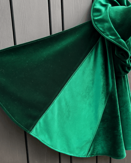 Zbliżenie na zielony, aksamitny materiał zebrany i przymocowany do ciemnoszarej drewnianej powierzchni.