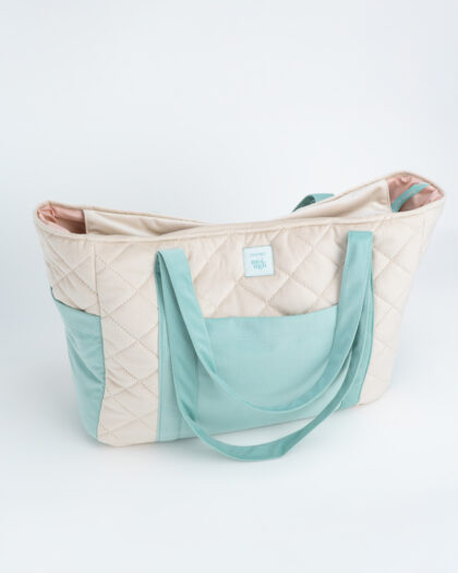 Beżowo-miętowa pikowana torba z długimi uchwytami i zewnętrzną kieszenią, na białym tle.