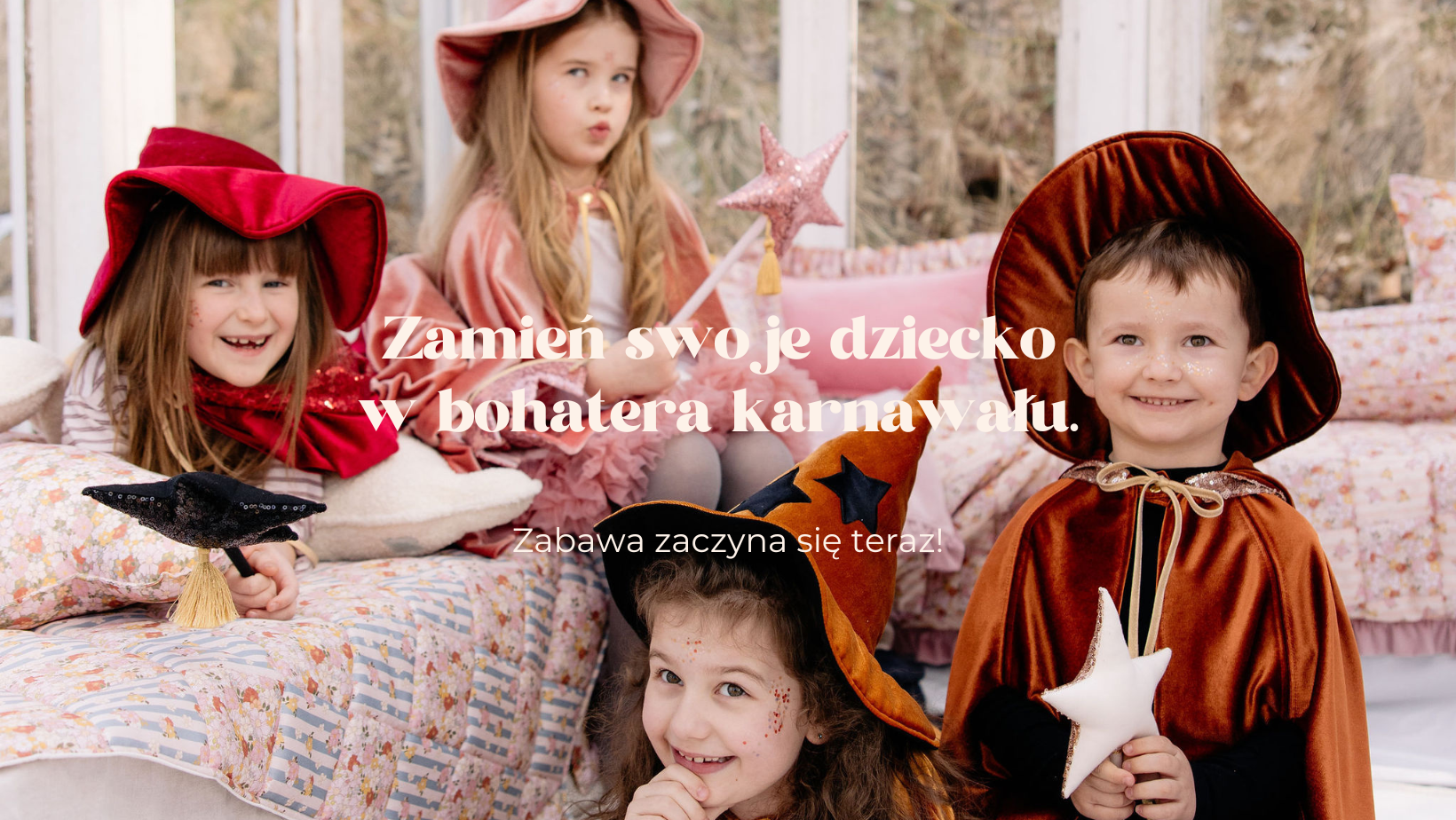 Czworo dzieci w kolorowych kapeluszach i kostiumach bawi się na łóżku w przytulnym pokoju.